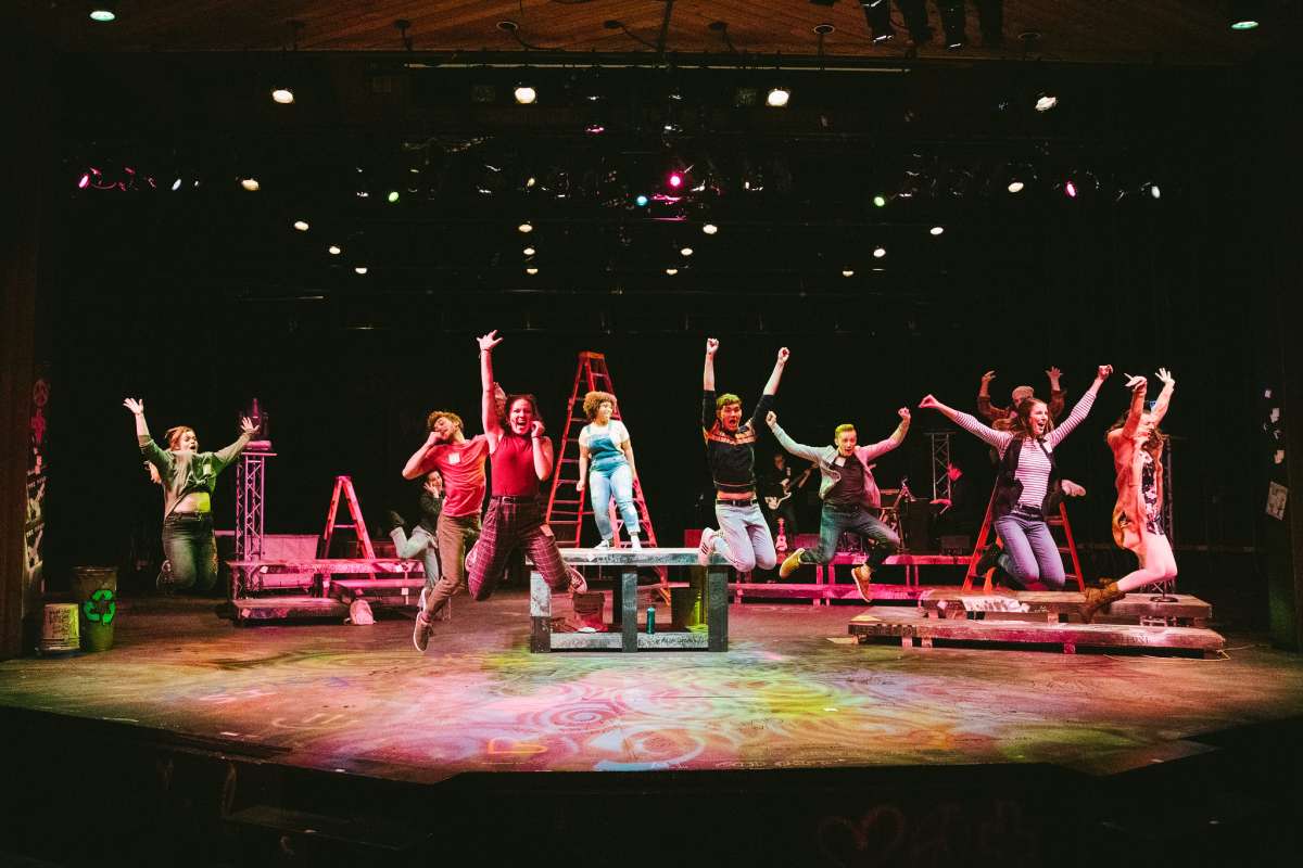 Students dancing and jumping on stage during a theater production
