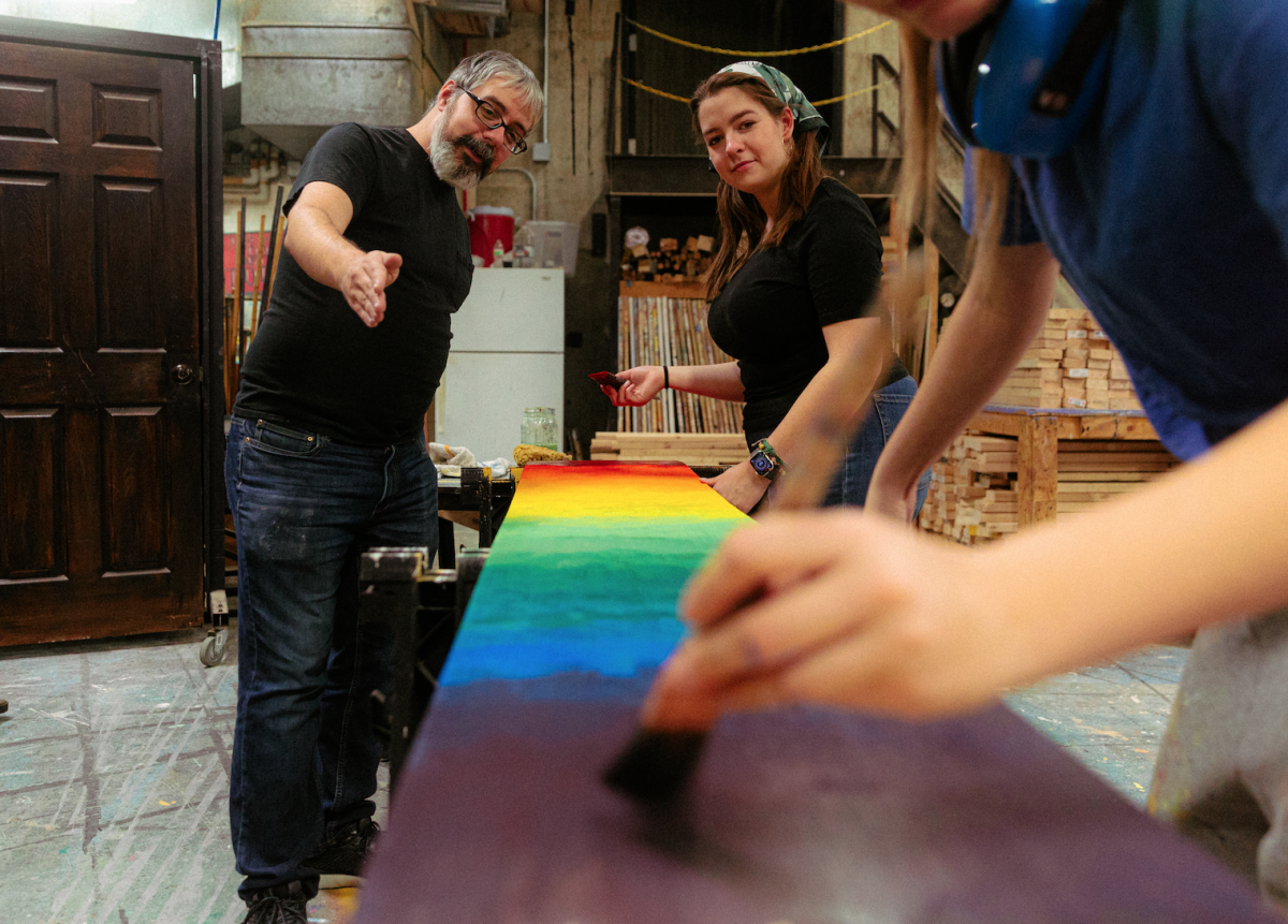 A professor instructing two students as they design a theater set.